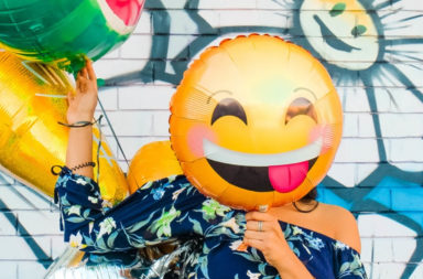 Woman with emoji balloon over face