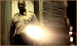 Policeman in Dark Floors shining a torch at the camera