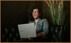 A woman wearing glasses sat at a laptop