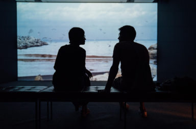 Two people sat in front an aquarium speaking