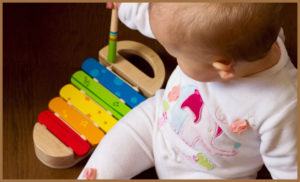 A baby playing with a glockenspiel