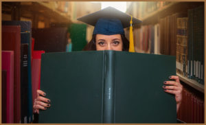 An autistic woman in a graduates hat reading a big book