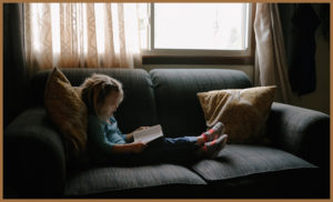 Autistic girl on sofa reading a book