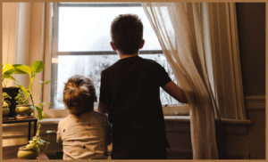 Two autistic children looking out of a window