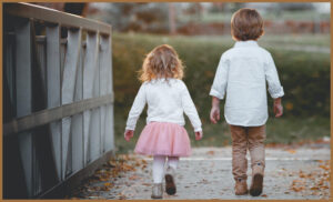 An autistic boy and girl walking across a bridge