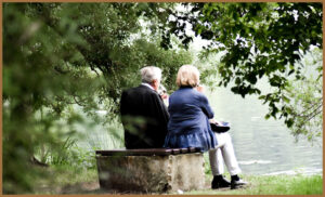 An elderly couple sat by a lake