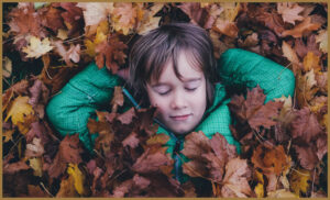 An autistic boy surrounded by leaves