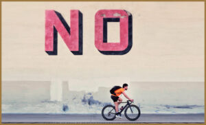 An autistic cyclist riding under a large 'no' sign